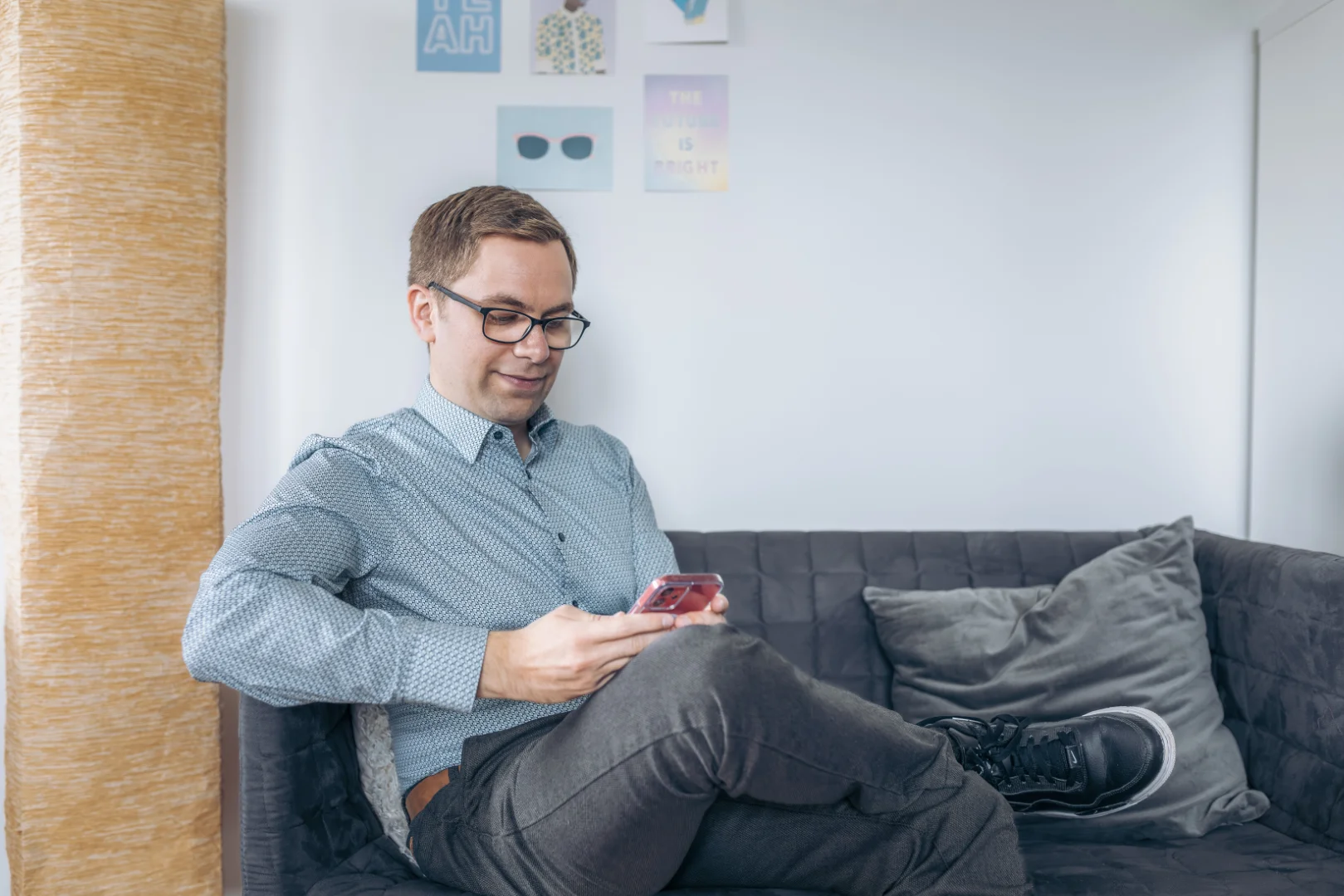 Nicolas Wazulek working on his cell phone on a sofa in the office.