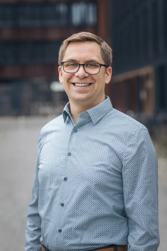 Portrait of Nicolas Wazulek outside in front of a modern building with blurred background.