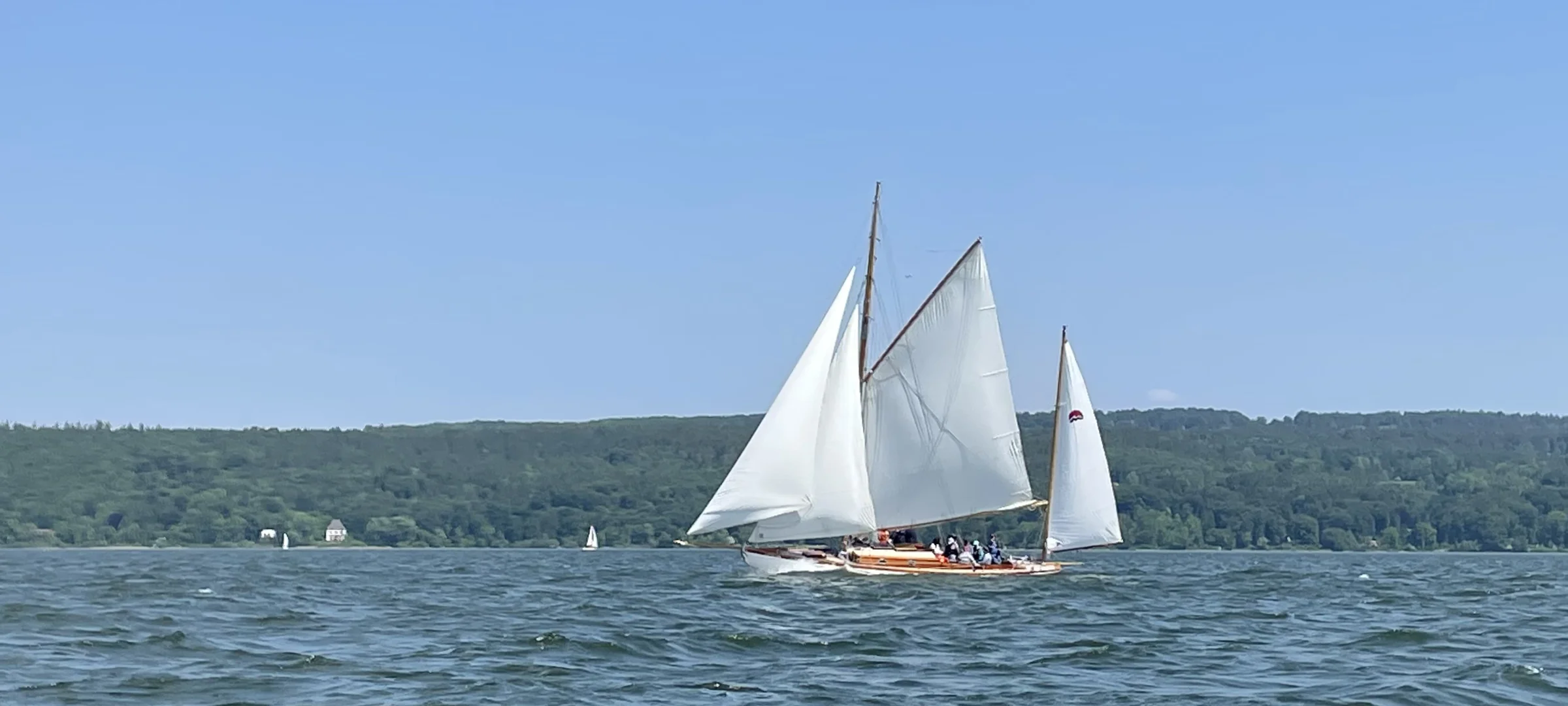 Picture of a sailing boat with white sails in the wind.